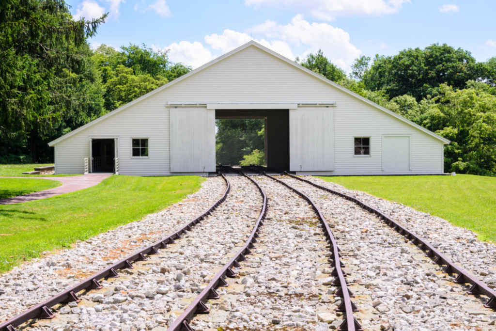Image of railroad track running through white building.